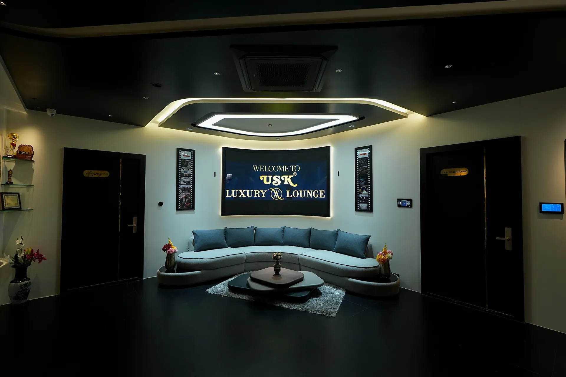 USK Luxury AV Lounge reception with curved sofa and illuminated welcome screen